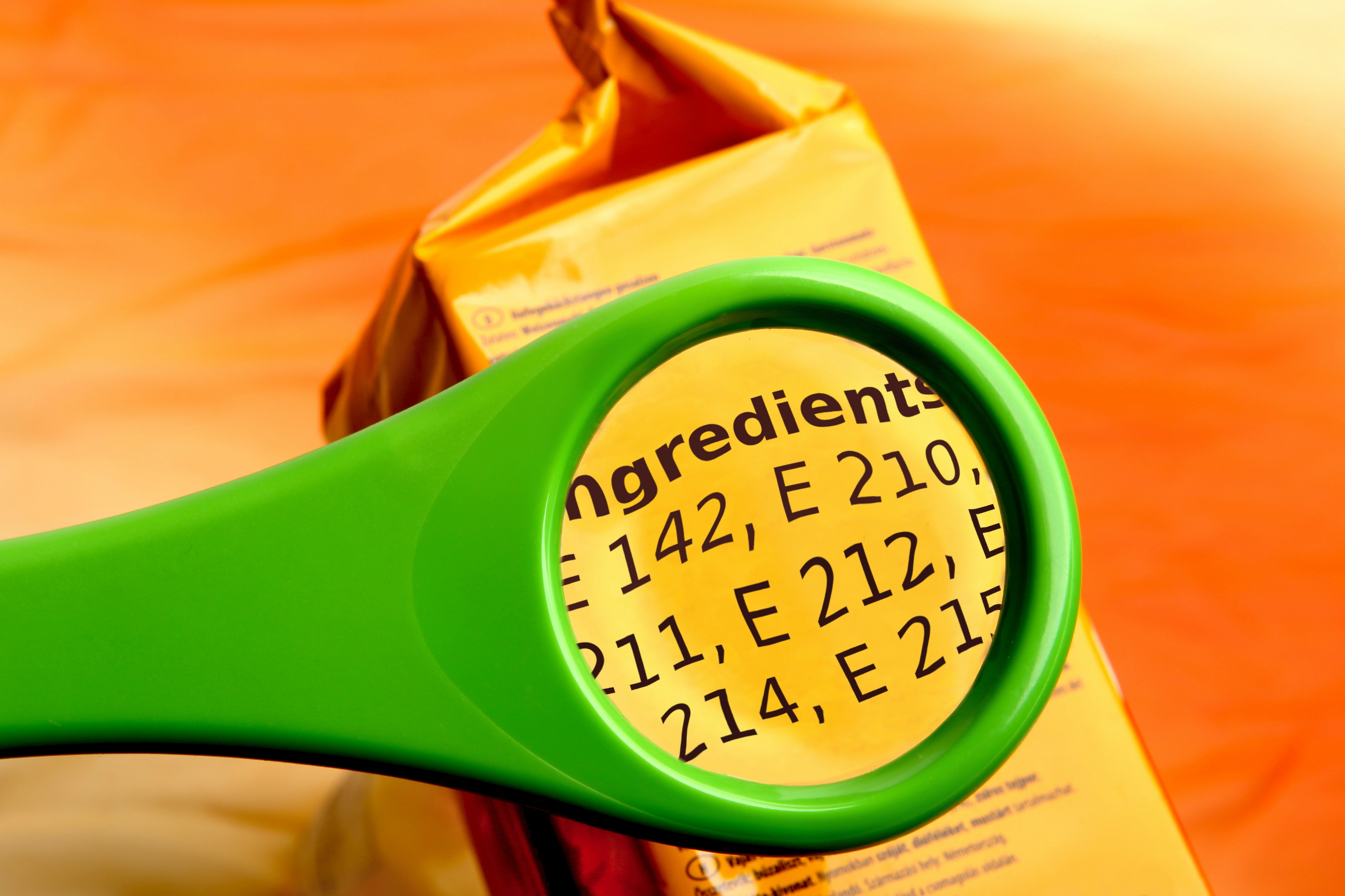Concept of reading ingredients list on food package with magnifying glass. Magnifying glass on food additives label.