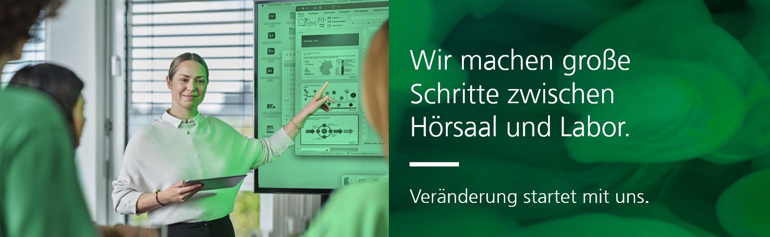 Eine Person präsentiert Inhalte auf einem großen Bildschirm und hält ein Tablet in der Hand, während mehrere Personen zuhören. Rechts daneben befindet sich ein Textfeld mit der Aufschrift: „Wir machen große Schritte zwischen Hörsaal und Labor. Veränderung startet mit uns.“ vor einem grün gefärbten Hintergrund mit unscharfen Strukturen.