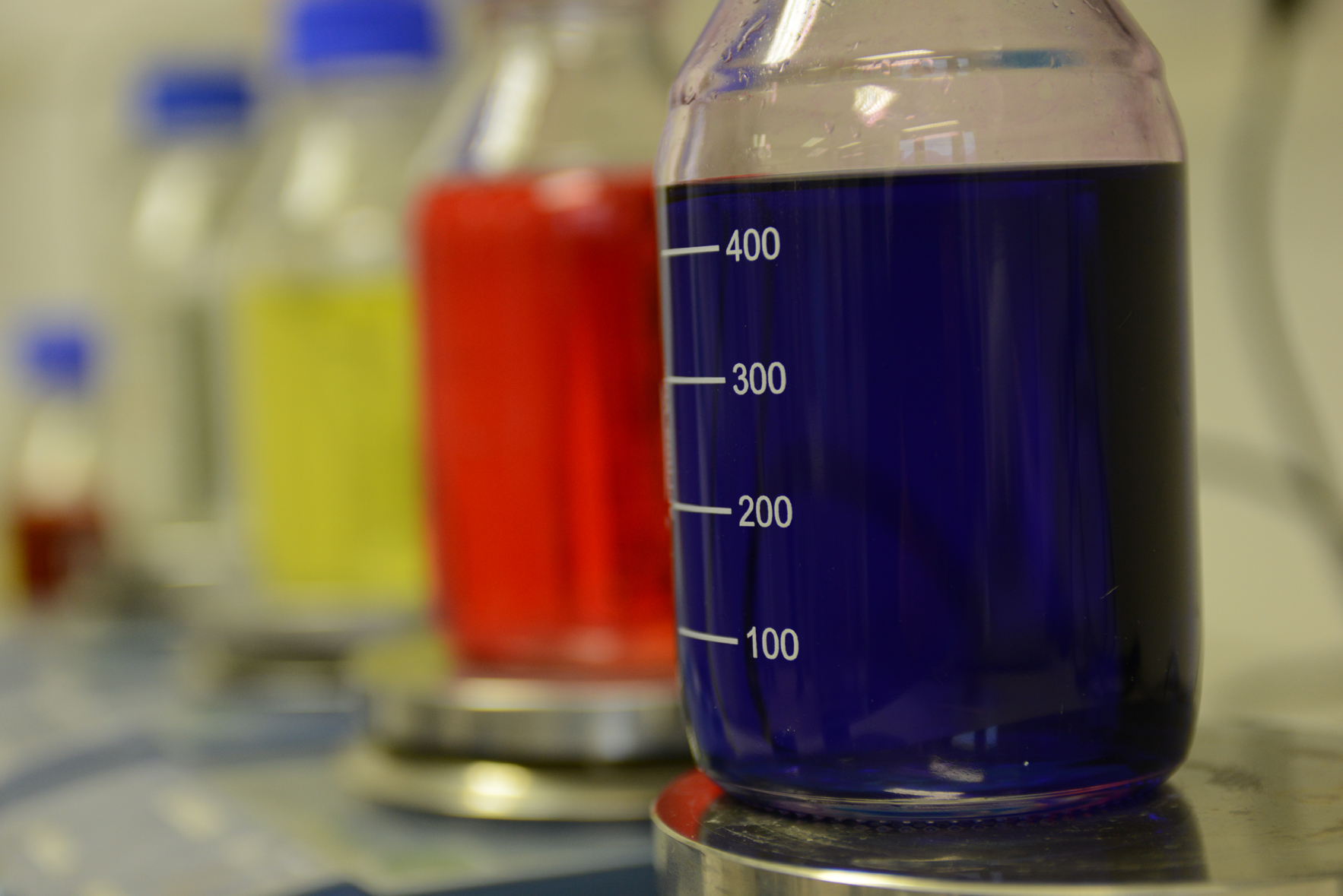 »Chemikaliensicherheit«: Von der Risikoanalyse zum sicheren Produkt Flaschen mit bunten Flüssigkeiten stehen in einer Reihe.