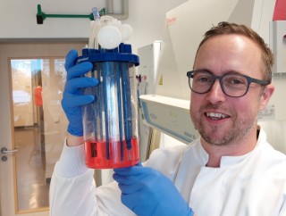 Nico Lachmann holding a reaction vessel.