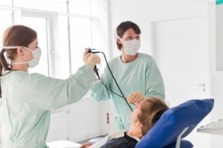 Doctor and medical assistant performing a bronchoscopy on a patient.