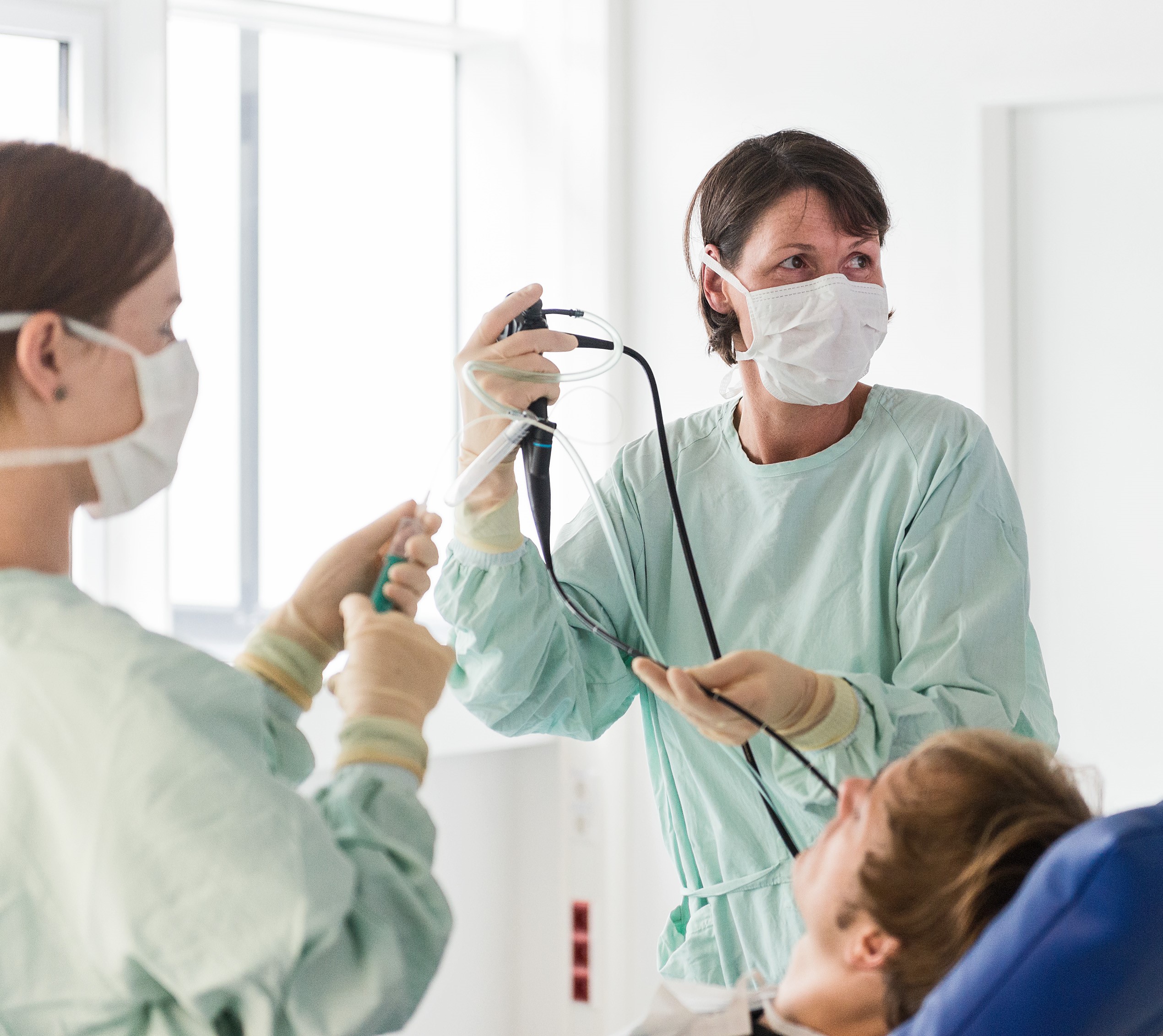 Doctor and medical assistant performing a bronchoscopy on a patient.